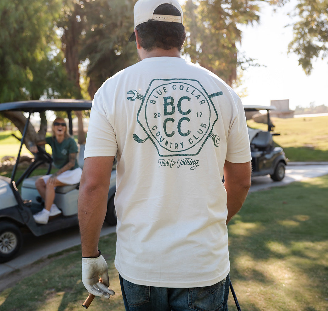 Man wearing white Blue Collar Country Club t-shirt on golf course