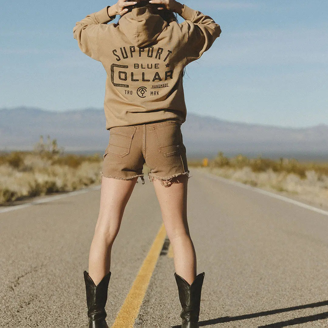 Hailey wearing the dune Nova hoodie and showing the Support Blue Collar slogan